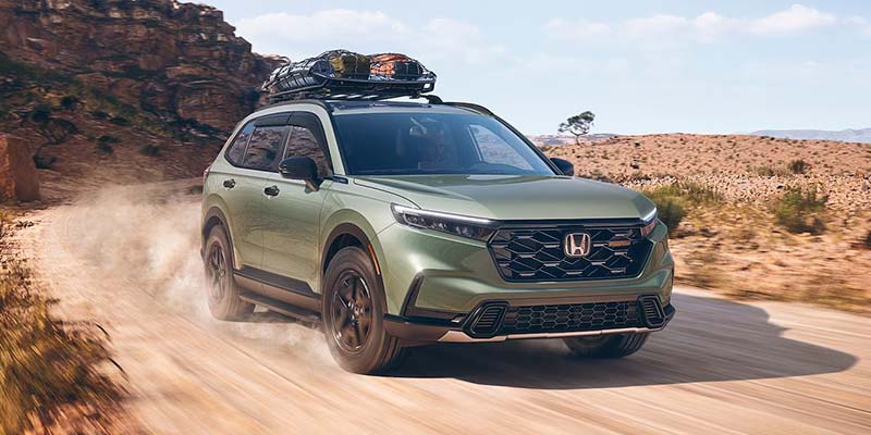 Green Honda CR-V driving on a dirt road
